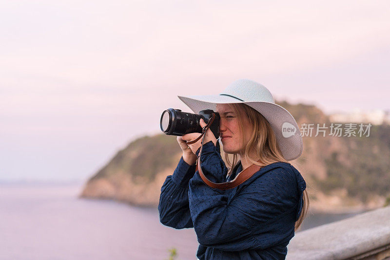 年轻的女人在海边拍摄照片