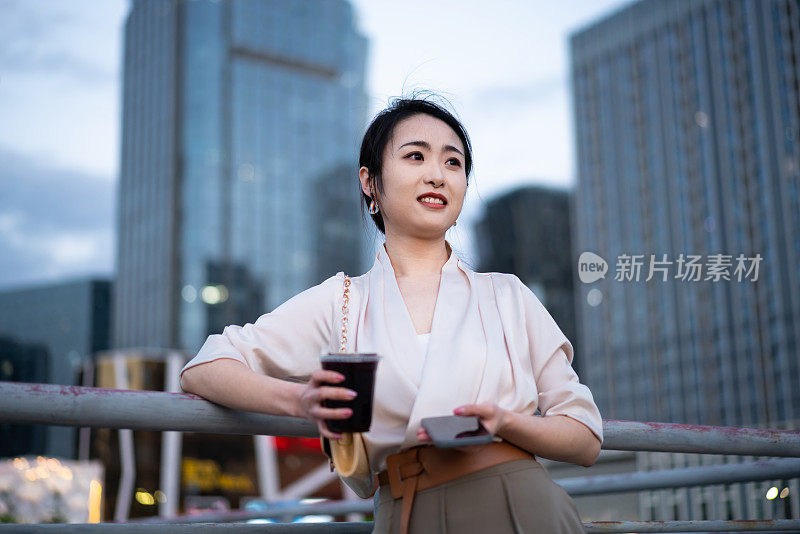 亚洲商业女性站在城市街头，写字楼背景，成功、自信的女性理念