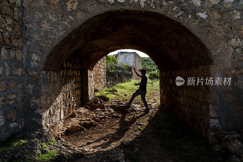 在乡村道路石拱下使用虚拟现实模拟器的人的图像。