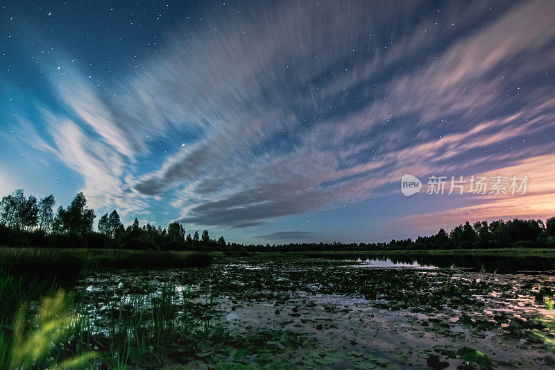 湖上的睡莲。月亮云。美丽的夜晚景观。夜空中的星星。长时间的曝光。夏天的星空。银河系。河。水