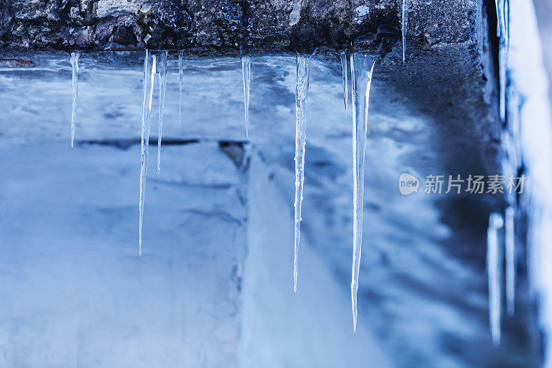 冰柱挂在屋顶上。冬天的背景。天气。气候。冰