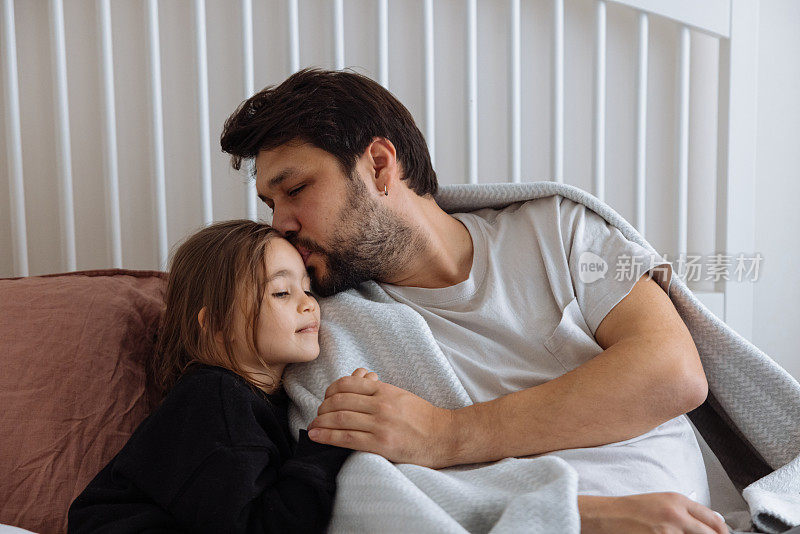 小女孩抱着爸爸，爱抚他，安慰他，让他平静下来。流感，疾病概念。