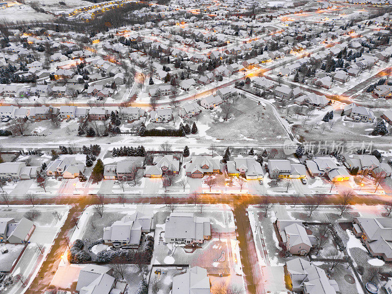 灯火通明的街道上被雪覆盖的房屋的城市景观。