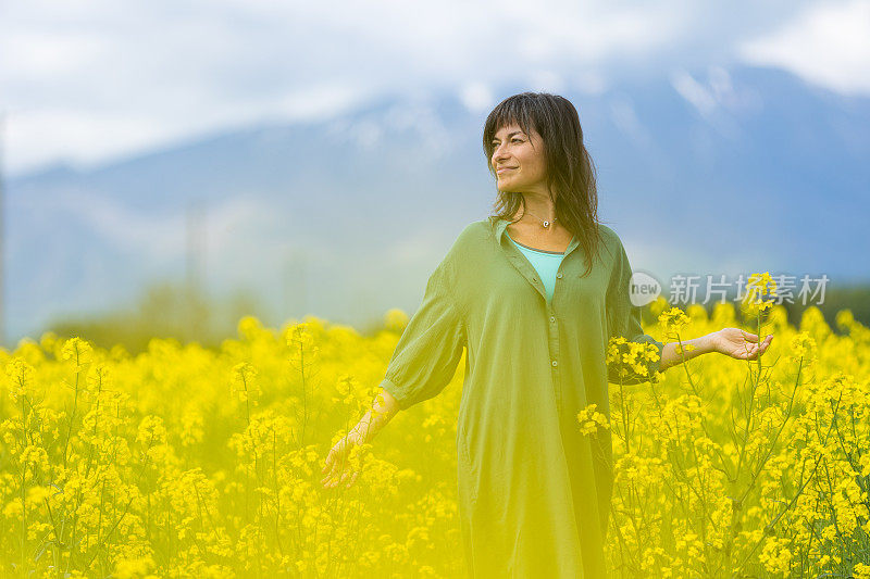 一位妇女在一片黄色的油菜花地里放松和享受户外活动