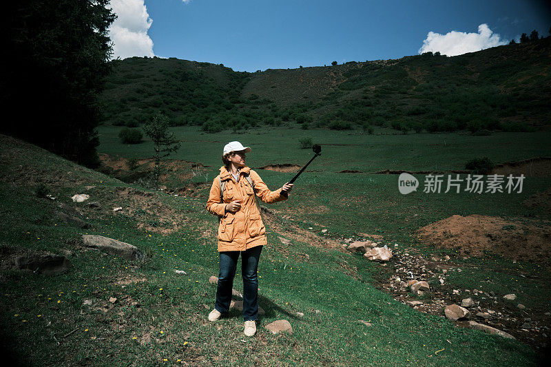 一位女背包客在山林里拍视频