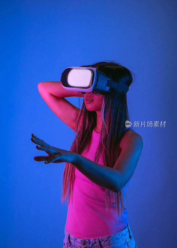 戴着现代VR眼镜的年轻女子在工作室里用霓虹灯探索虚拟现实