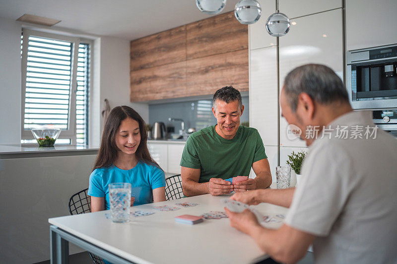 可爱的多代亚洲家庭在家庭餐厅玩纸牌游戏