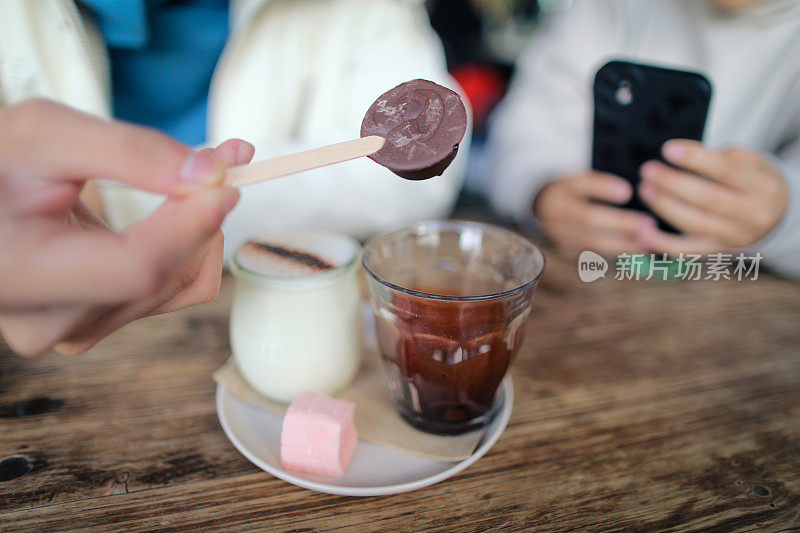 亚洲男孩正在展示他的热巧克力牛奶，女孩正在用手机拍照
