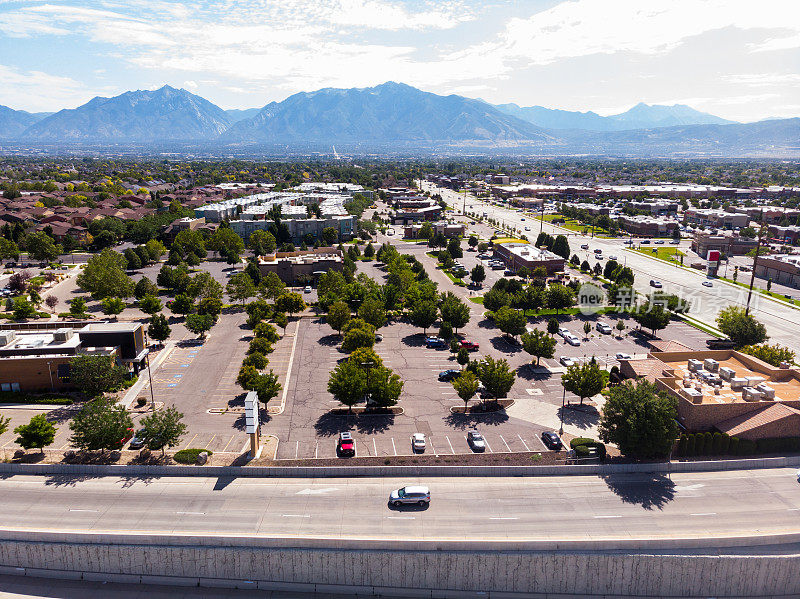 从空中俯瞰盐湖城郊区的广阔景象:发展中的社区、熙熙攘攘的道路和商业中心，被遥远的山脉和城市的活力所包围。