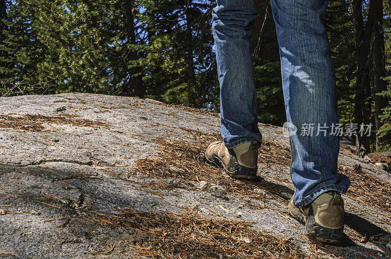 徒步旅行者穿着登山靴穿过岩石和松针