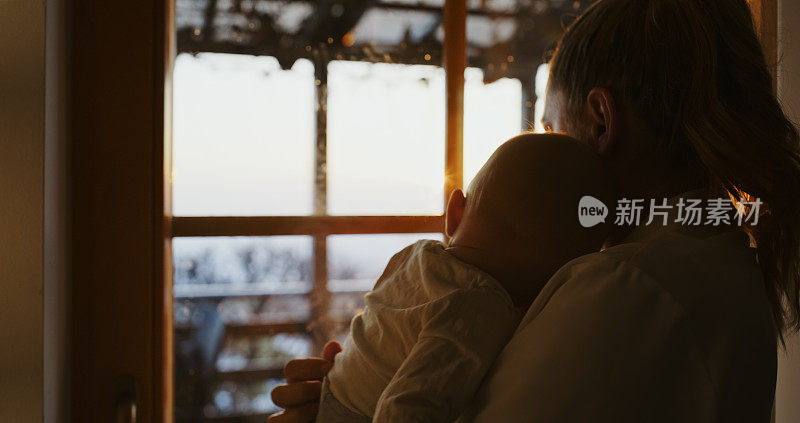 母亲的爱。夕阳西下，母亲抱着熟睡的婴儿在窗边