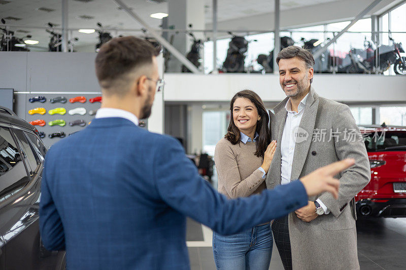 顾客在汽车陈列室向销售人员购买汽车
