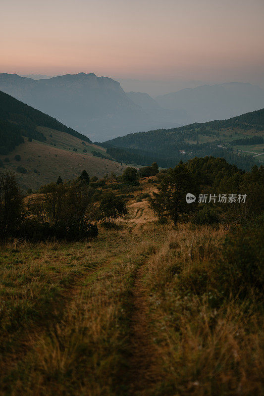 宁静的风景，绿色的小山，一条土路和遥远的山脉。特伦蒂诺完美的度假胜地