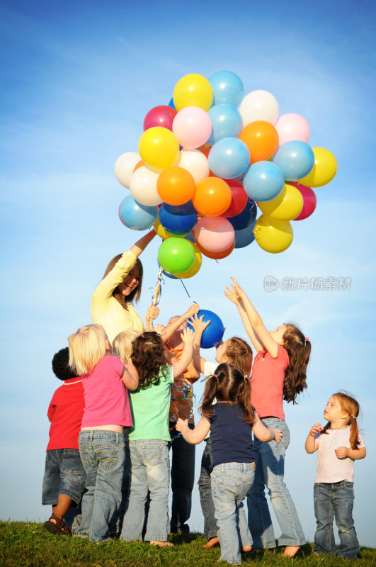 一群兴奋的孩子伸手去拿气球