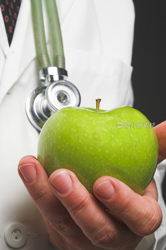 一个穿着白衣的医生拿着一个青苹果