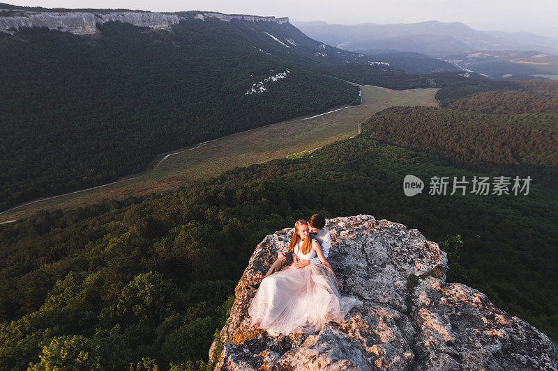 新婚夫妇站在悬崖边，景色迷人