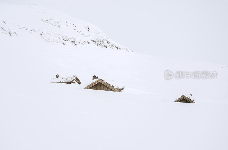 三间传统的原木小屋几乎完全被雪覆盖