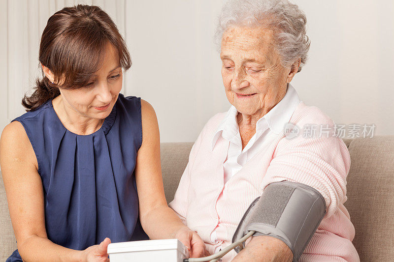 年长的女性和护理人员正在测试血压