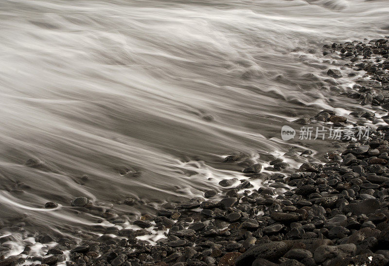 在黑岩海滩上运动的波浪