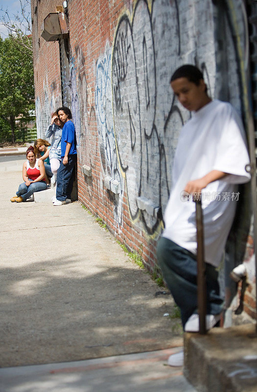 几个西班牙裔的孩子坐在一堵砖墙旁边