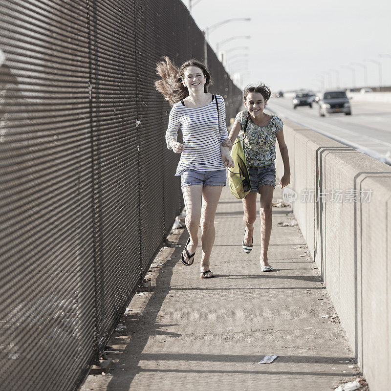 两个女孩正走过工业区的一座桥