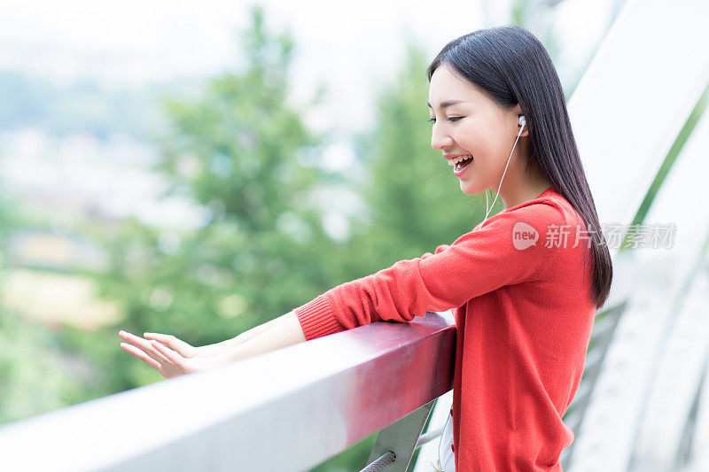 年轻女孩用智能手机的耳机听音乐