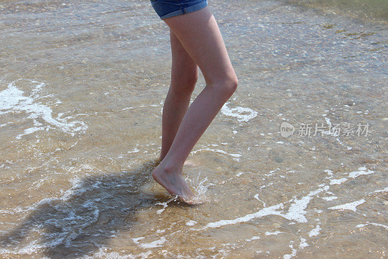 女孩在海浪中划桨，腿，水，赤脚，海边沙滩