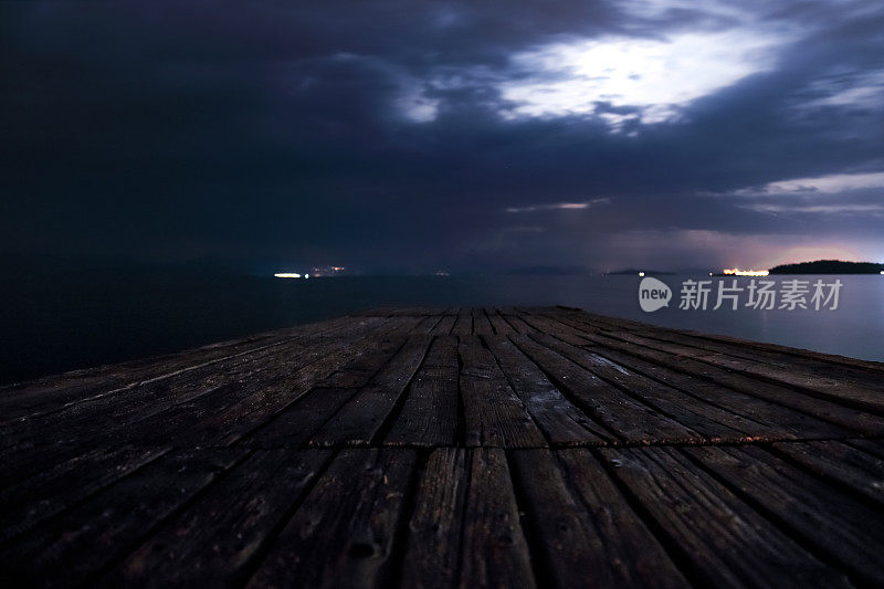 夜晚的木制码头和月光下的暴风雨云