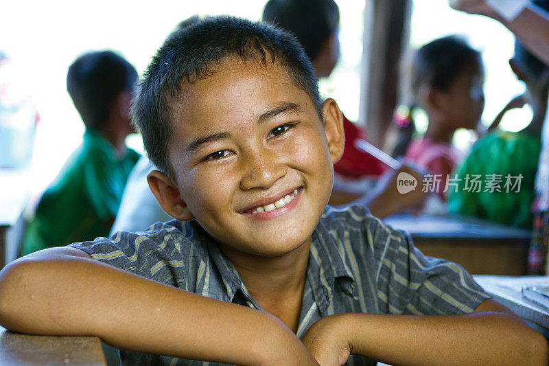 小男孩在学校的课桌前微笑
