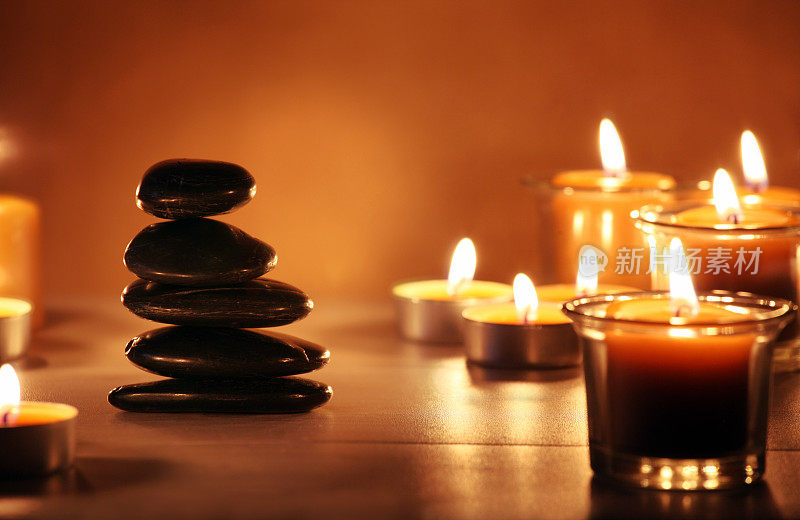 用木头桌子上的蜡烛来平衡禅宗石和鹅卵石