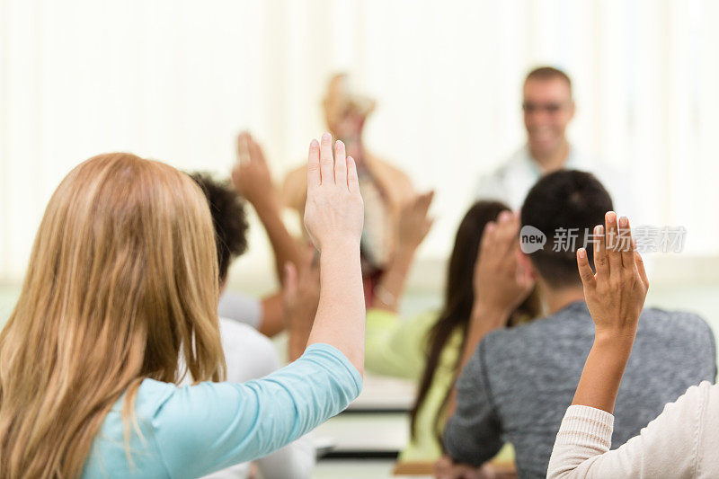 高中学生举手的后视图