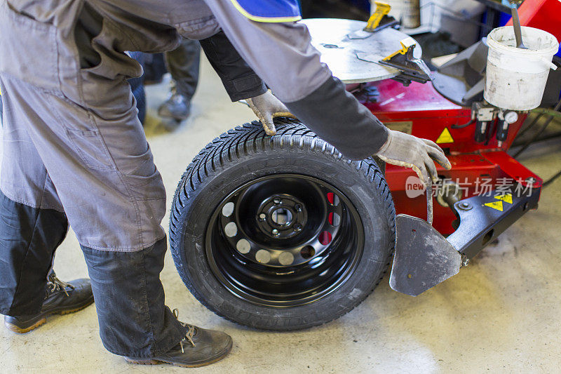 在汽车修理厂…汽车修理工正在平衡冬季轮胎