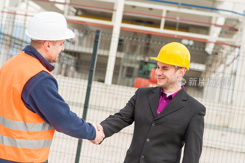 建筑师和建筑工人握手。