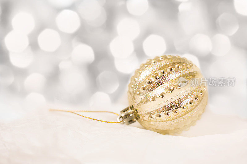 白雪上点缀着白色灯光的金色圣诞装饰品。