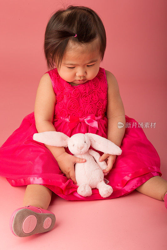 亚洲蹒跚学步的孩子抱着粉红色的兔子玩具