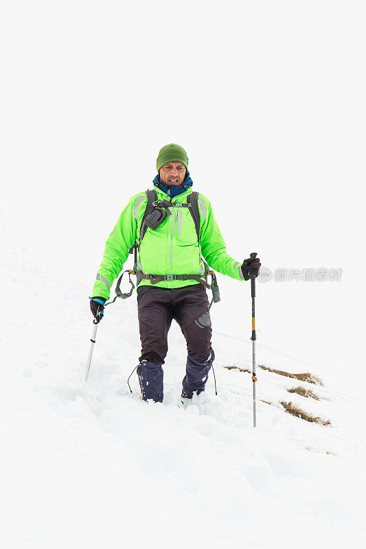 穿着雪鞋在白雪覆盖的山上行走的徒步者