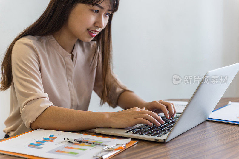 特写的女人手打字笔记本旁边的文件和报告