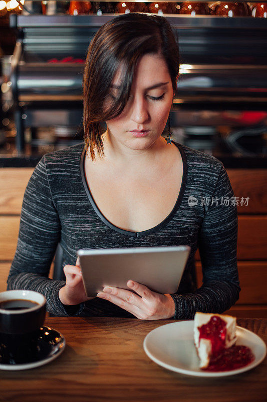 一个年轻女子在咖啡店里用平板电脑工作