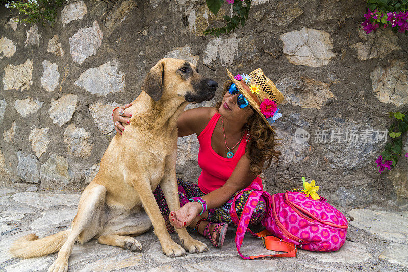 女游客在抚摸着狗。土耳其穆格拉达卡。