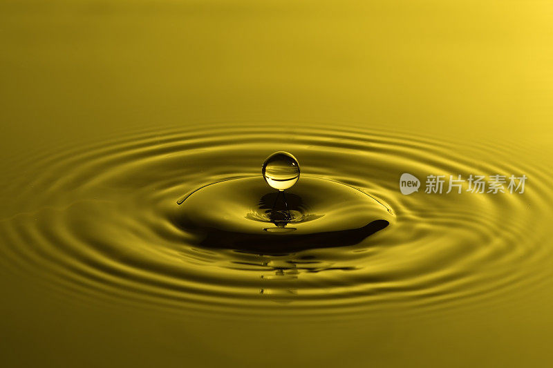 水滴近距离与同心涟漪在五颜六色的黄色表面