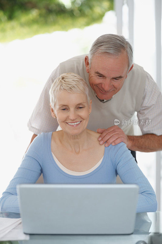 微笑的老年男女使用笔记本电脑