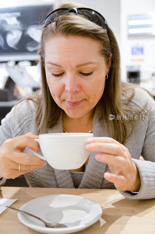 一个女人在喝咖啡前吹着热咖啡