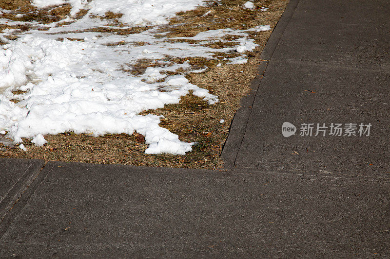 在人行道的角落里，满是枯草和积雪