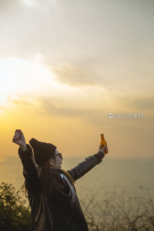 夕阳西下，年轻女子喝着啤酒