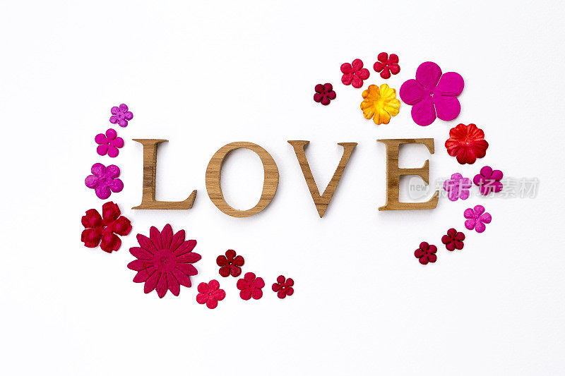 木制爱情文字与彩色纸花框架在白色纹理的背景