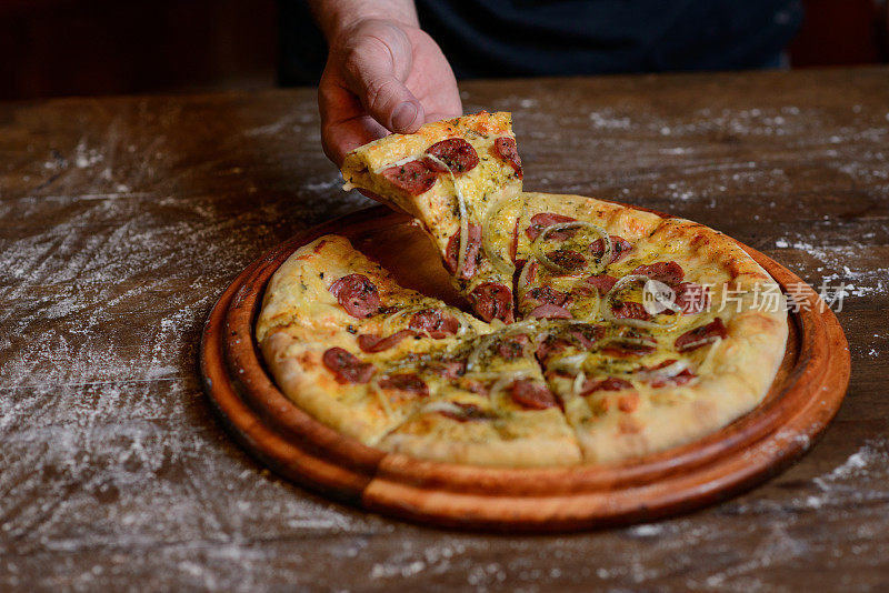 乡下的桌子上放着洋葱辣香肠披萨