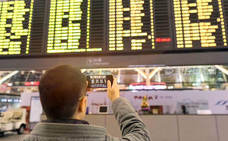 旅客在机场候机楼看航班信息板
