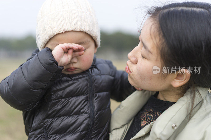 年轻的母亲在草地上抱着儿子