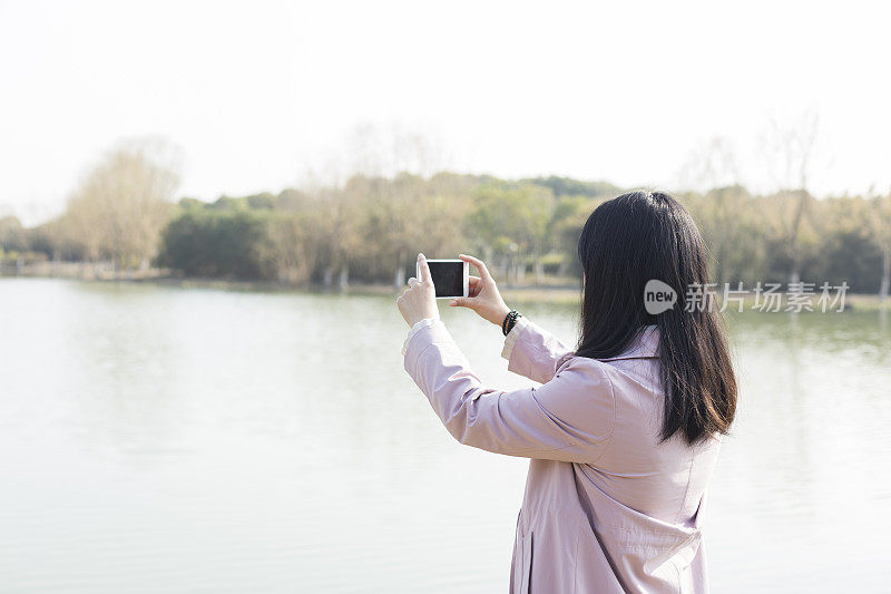 一个春天的下午，用智能手机拍照的女人