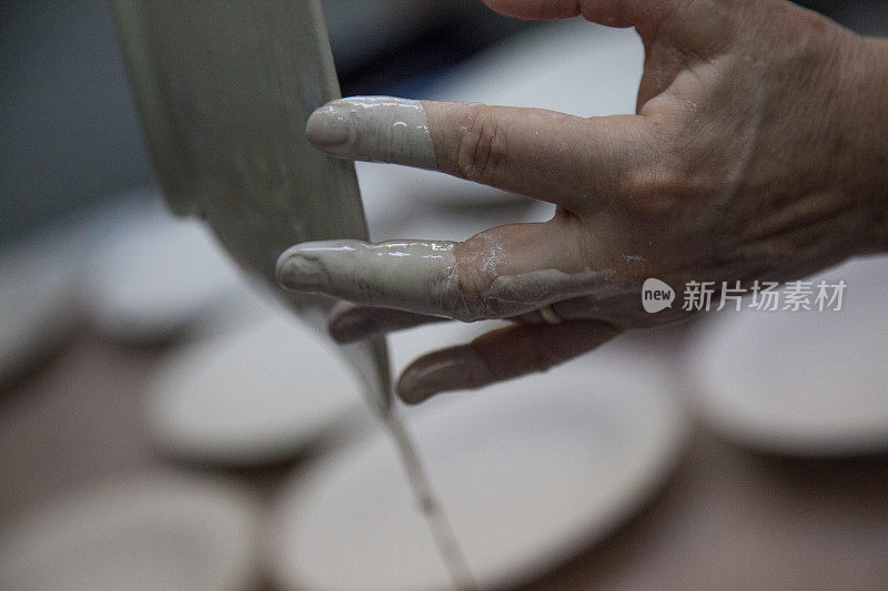 盘子滴水后浸在陶瓷釉面前烧制，女人的手，戴着结婚戒指，艺术家的手